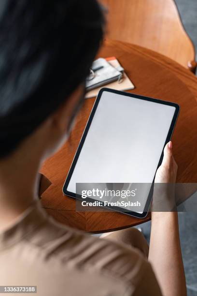 over the shoulder view of a digital tablet with a blank screen in the hands of an unrecognizable businesswoman (copy space) - tablet screen stockfoto's en -beelden