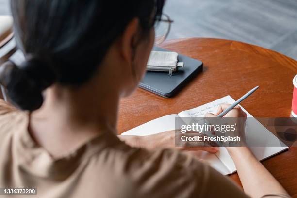 over the shoulder view of a college student studying at a local cafe - 2020 diary stock pictures, royalty-free photos & images