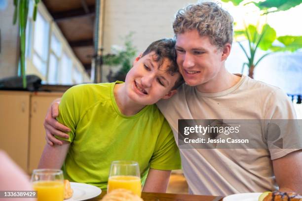 a boy with autism hugs his brother at breakfast - autismo foto e immagini stock