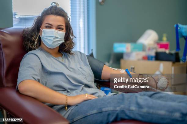 une jeune femme masquée heureuse de donner du sang - prise de sang photos et images de collection