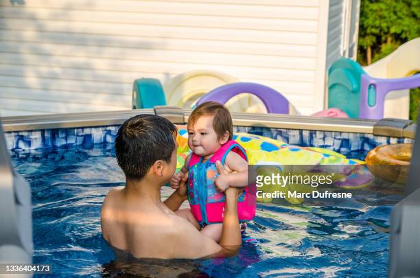 chinese father holding baby girl in pool - métis stock pictures, royalty-free photos & images