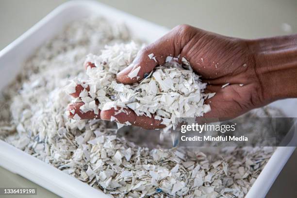 primo piano della mano del giovane che tiene bilance di plastica riciclata all'interno del lotto - centro di riciclaggio foto e immagini stock