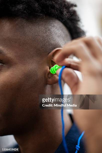 close up of industrial laborer putting on safety earplugs - ear protection stock pictures, royalty-free photos & images