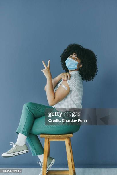 shot of a woman showing a peace sign after receiving the covid-19 vaccine - vaccine confidence stock pictures, royalty-free photos & images