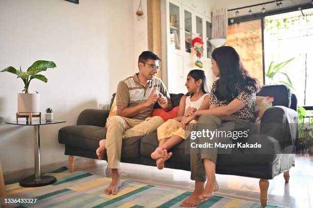 parents sitting on a sofa and having a serious discussion with their daughter - indian mother and child stock pictures, royalty-free photos & images