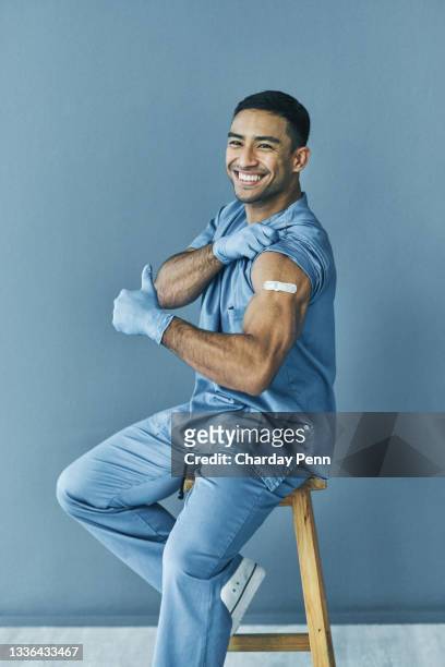 shot of a medical practitioner showing thumbs up after receiving the covid-19 vaccine - man studio shot stock pictures, royalty-free photos & images