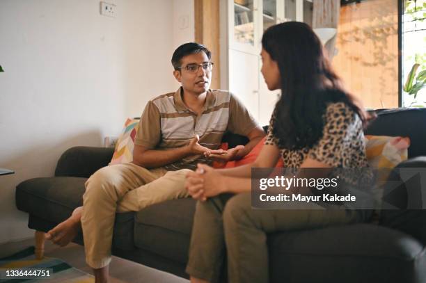 mature couple having a serious discussion sitting on a sofa in living room - indian living room stock-fotos und bilder