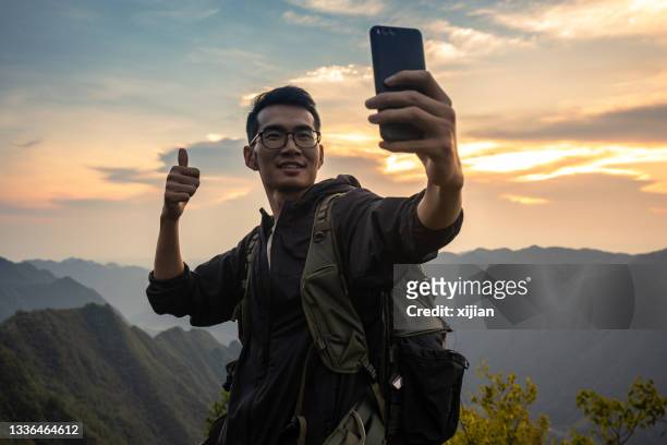 hiker taking a selfie with smart phone - guy on top of mountain stock pictures, royalty-free photos & images