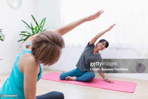a woman taking a private pilates lesson at the instructor's home studio. - 40s woman t shirt studio imagens e fotografias de stock