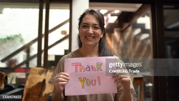 frau hält papier mit "danke" zu hause geschrieben - thank-you-englischer-satz stock-fotos und bilder
