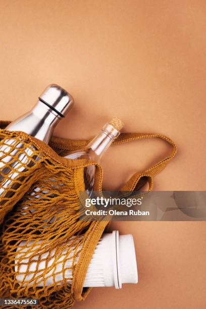 iron, glass and eco bottles in a string bag - reusable water bottle - fotografias e filmes do acervo