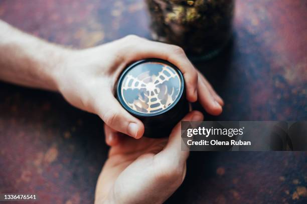 man's hands grinds marijuana in a grinder - hemp stalks stock pictures, royalty-free photos & images