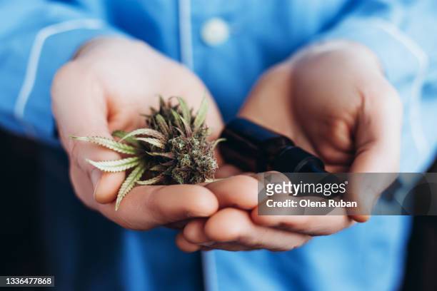close-up of medical marijuana and oil in dark glass jar in the hands - cannabis terapeutica foto e immagini stock
