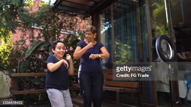 boy dancing with grandmother and filming it at home - dance challenge stock pictures, royalty-free photos & images