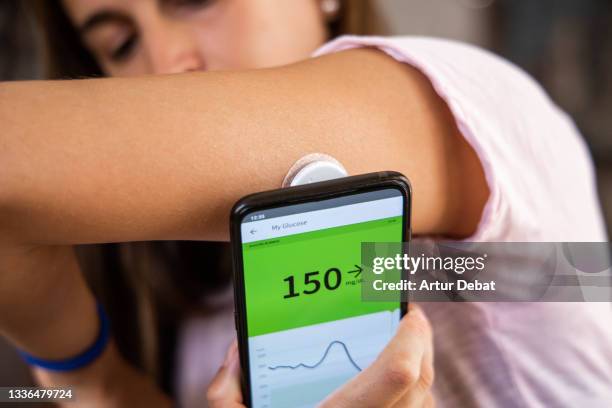 woman monitoring herself the levels of glucose in blood using smart phone technology. - glucose stockfoto's en -beelden