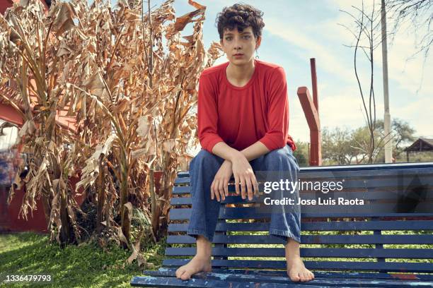 portrait of young woman sitting on bench in park - non binary stereotypes stock pictures, royalty-free photos & images