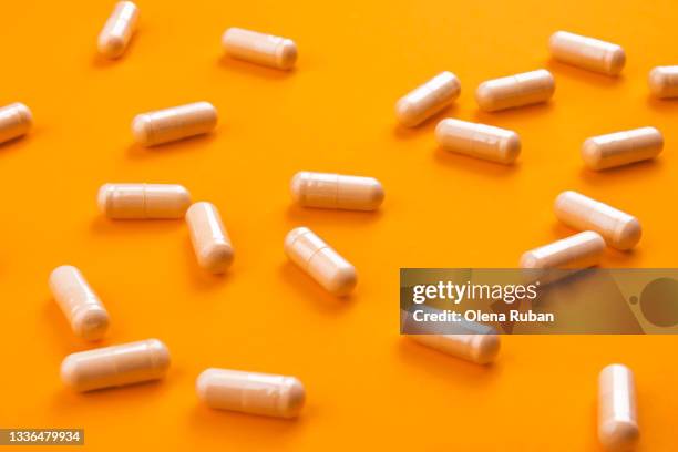 beige pills on a bright orange background - space capsule stock pictures, royalty-free photos & images