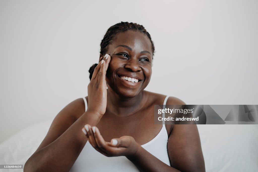 Cuidado de la piel usando crema cosmética para la piel Mujer con piel negra