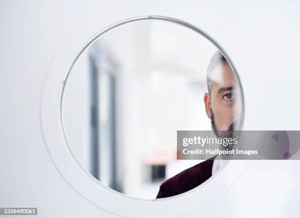 front view of cut out face of businessman looking at camera through window in door. - mirror object stock pictures, royalty-free photos & images