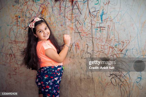 funny cute little girl drawing with marker on wall at home. young artist painting on wall at living room - indian painting stock pictures, royalty-free photos & images