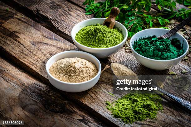 ground spirulina, maca and moringa on rustic table - spirulinabacterie stockfoto's en -beelden