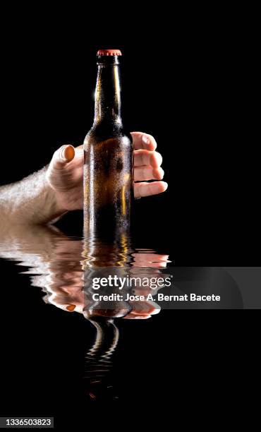 hand of a man clutching a beer bottle reflected on a water surface. - bottle condensation stock pictures, royalty-free photos & images