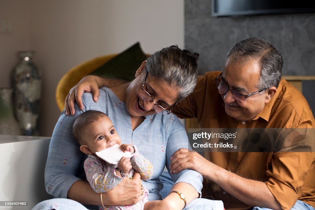 Happy grandparents with baby grandson at home