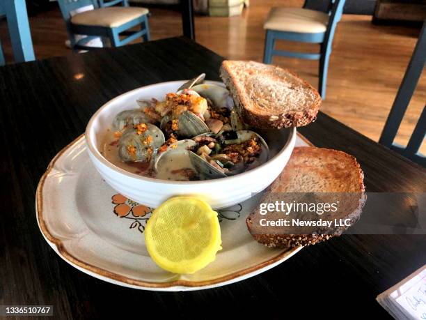 Bowl of clams steamed in a chowder broth and topped with bacon at Swept Away restaurant in Bay Shore, New York on August 19, 2021.