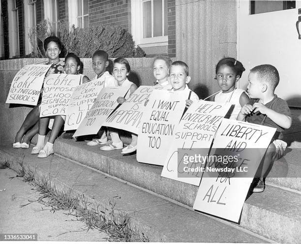 On August 2 children sit on the steps of Malverne HIgh School in Malverne, New York with picket signs supporting integrated education. Three people...