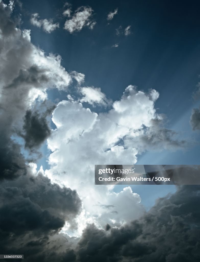 Low angle view of sunlight streaming through clouds
