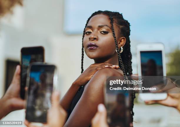 shot of a young woman having a picture taken on multiple cellphones - hipster stock pictures, royalty-free photos & images