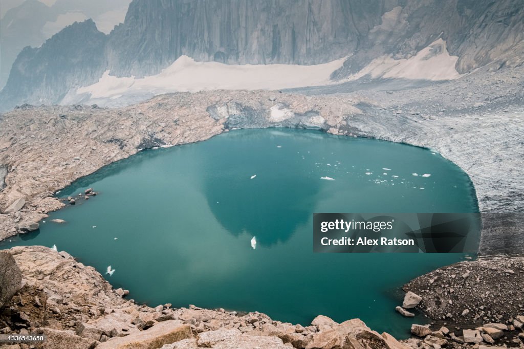 Aerial view of a glacier flowing into a alpine lake with a mountain reflection