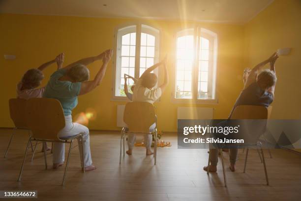 active senior women: yoga class on chairs - chair stock pictures, royalty-free photos & images