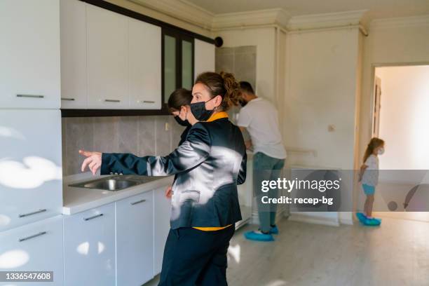 female real estate agent showing unfurnished house to married young couple with their daughter - search new home stock pictures, royalty-free photos & images