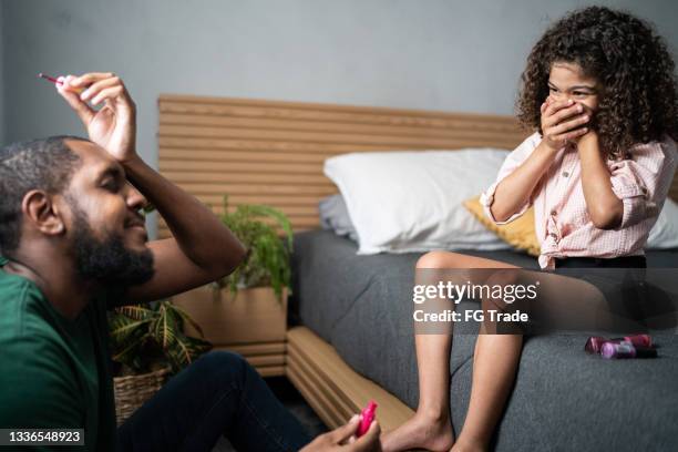 father making a mistake while painting daughter's toenails at home - mistaken identity stock pictures, royalty-free photos & images