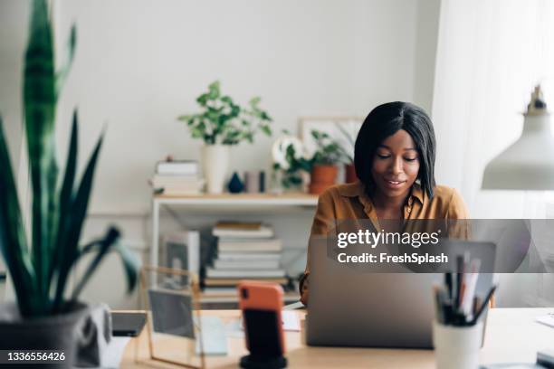 cheerful business woman working from home on laptop computer - yellow shirt stock pictures, royalty-free photos & images