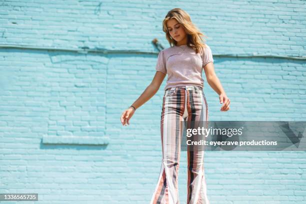 teenage female standing in front of blue brick wall urban photo series - flare pants bildbanksfoton och bilder