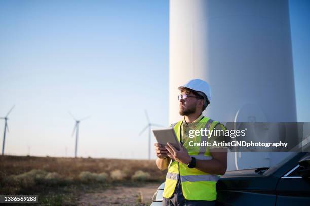 junger ingenieur, der windkraftanlagen vor ort mit einem digitalen tablet betrachtet und überprüft - engineer stock-fotos und bilder