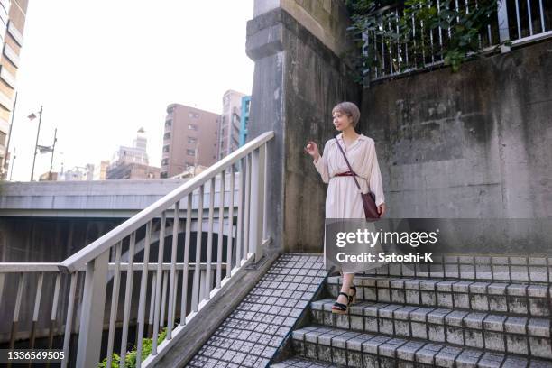 young woman walking down stairs, looking at view - portrait looking down stock pictures, royalty-free photos & images