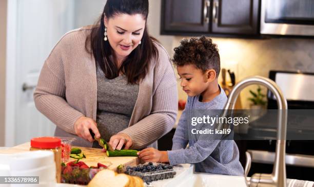 little boy helping mother make lunch in kitchen - 啤酒肚 個照片及圖片檔