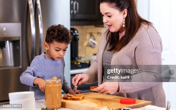 multi-ethnic mother, son making peanut butter sandwiches - peanut butter and jelly sandwich stockfoto's en -beelden