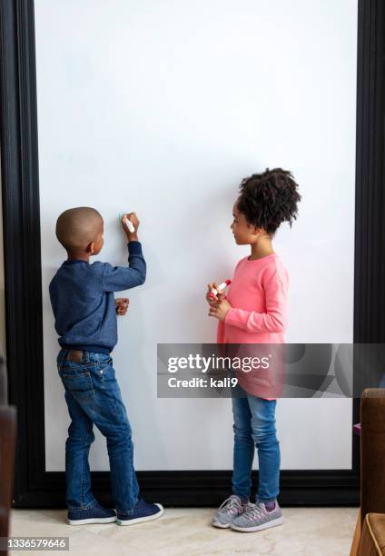 two african-american children writing on whiteboard - girl looking over shoulder stock pictures, royalty-free photos & images