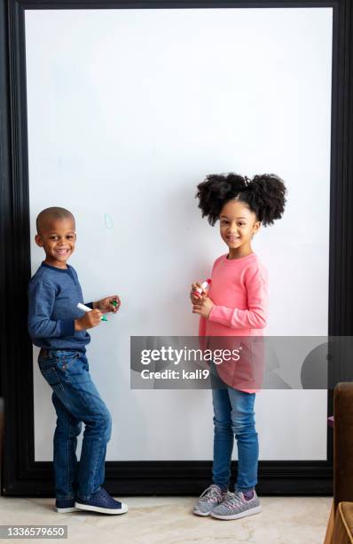 zwei afroamerikanische kinder stehen am whiteboard - two kids playing with hose stock-fotos und bilder