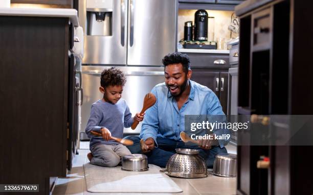 ragazzo e padre sul pavimento della cucina usando pentole come tamburi - jamaican ethnicity foto e immagini stock