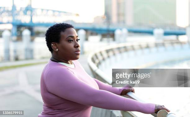 ernsthafte afroamerikanische frau im stadtpark, denkt nach - fat black man stock-fotos und bilder