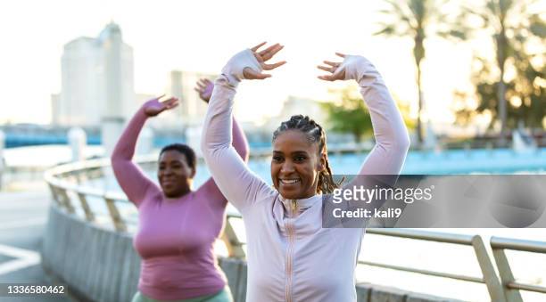 dos mujeres afroamericanas haciendo ejercicio al aire libre, calentamiento - long sleeved fotografías e imágenes de stock