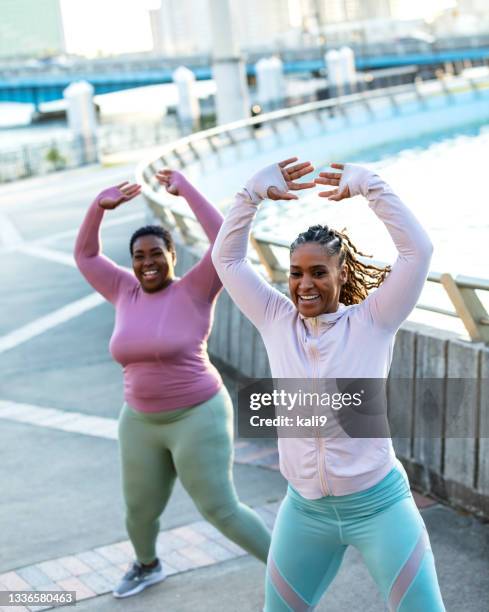 two african-american woman doing jumping jacks outdoors - jumping jack stock pictures, royalty-free photos & images