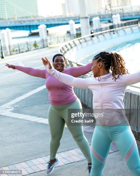 two african-american woman doing jumping jacks outdoors - jumping jack stock pictures, royalty-free photos & images