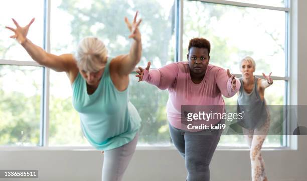 three mature women taking yoga class, in warrior 3 pose - only mature women stock pictures, royalty-free photos & images