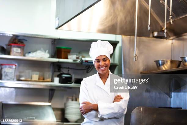 female chef standing in restaurant kitchen, arms crossed - kokkin stockfoto's en -beelden